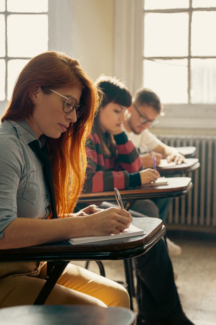 Services Students attentively writing notes during a classroom lecture in a university setting.
