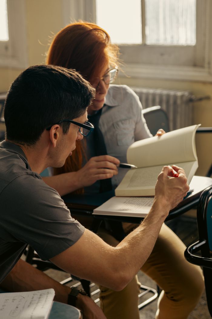 Services Two students discussing and reading a book in an academic setting in Buenos Aires.